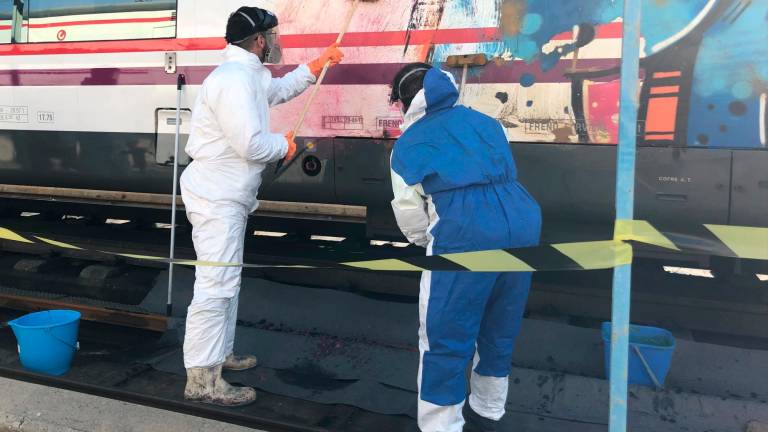 Dos personas limpiando un grafiti en un tren de Renfe. FOTO: rENFE