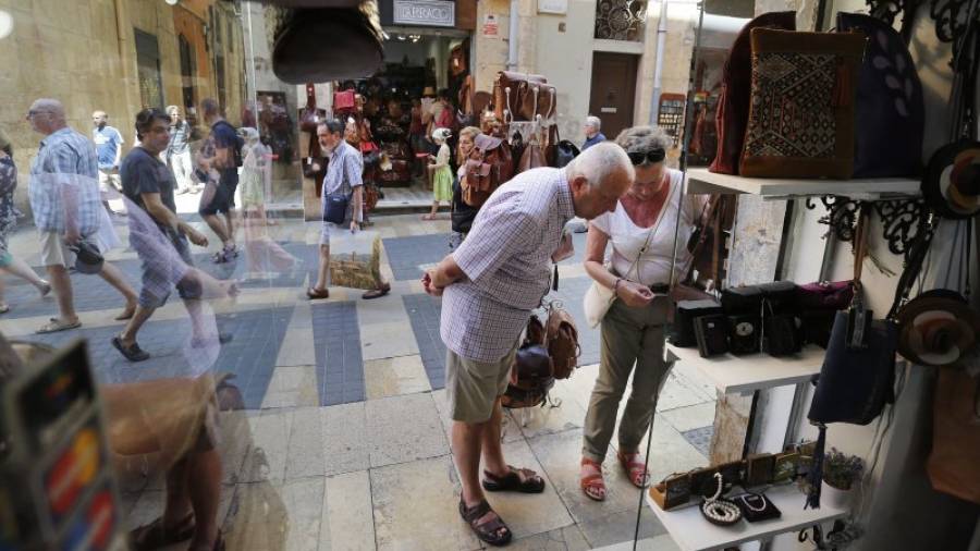 Dos turistas miran el escaparate de uno de los establecimientos de la Part Alta dedicado a la venta de productos de piel y accesorios. Foto: pere ferré