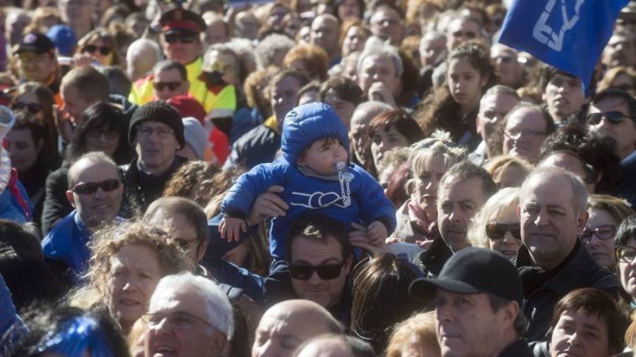 Un niño pequeño, ataviado con un abrigo azul de la PDE, es alzado en brazos entre la muchedumbre, ayer al mediodía. Foto: Joan Revillas