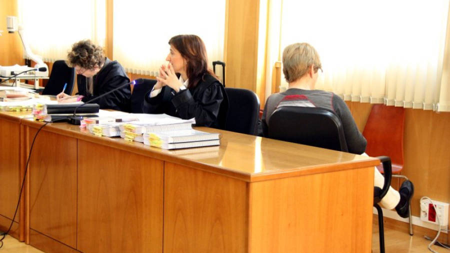 L'acusada, Remei Barrera, asseguda d'esquenes al costat de la seva advocada al banc dels acusats de l'Audiència de Tarragona.