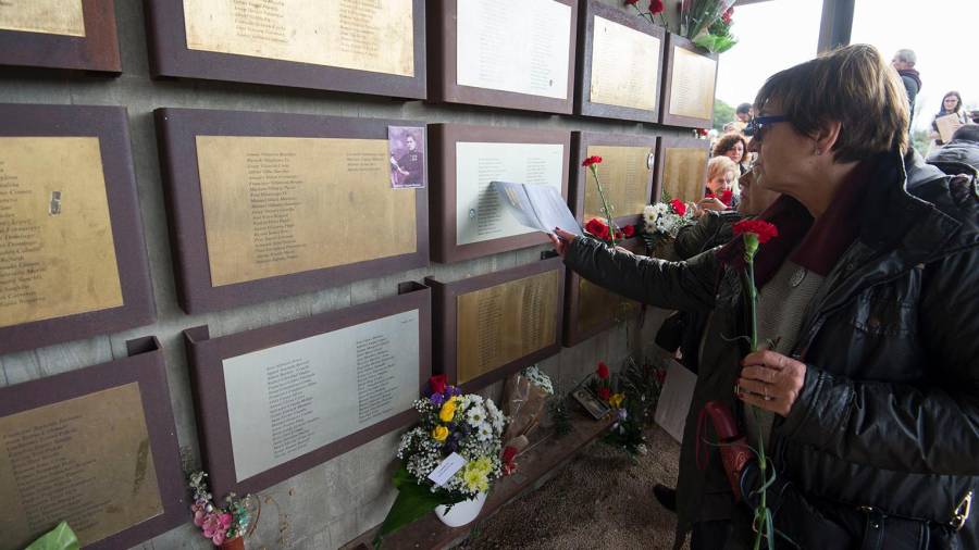 Els assistents buscaven entre les plaques del memorial els noms dels seus familiars i hi deixaven flors i escrits. FOTO: Joan Revillas