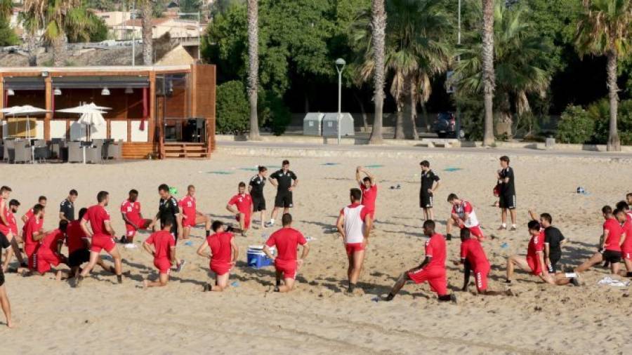 La plantilla al completo estirando en el entrenamiento realizado el pasado martes en la playa de la Arrabassada. Foto: Lluís Milián