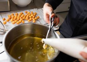 Adrià Aguilera, de Cal Jan, en Torredembarra, corta las pìezas de pasta antes de freírlas: «A mí me gustan así, recién fritos, con el café». Foto: Àngel Ullate