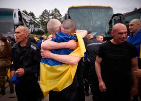 Prisioneros ucranianos intercambiados en virtud de un acuerdo entre Rusia y Ucrania se abrazan al ser liberados, envueltos en la bandera ucraniana. Foto: Gobierno de Ucrania