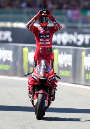Bagnaia celebra la victoria en Silverstone encima de su moto. FOTO: EFE