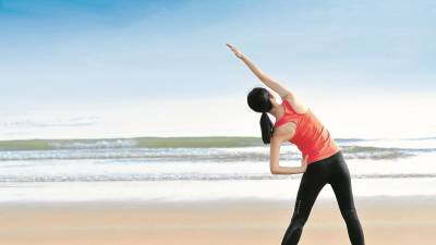 Attractive woman stretching legs after run on beach - Attractive woman stretching legs after run on beach Attractive woman stretching legs after run on beach