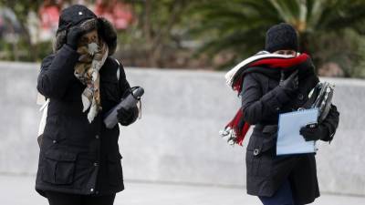 Dos mujeres se abrigan debido al frío y al viento durante la mañana de hoy