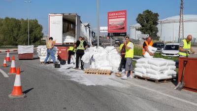 La carga extendida por la carretera y los servicios de emergencias y los operarios trabajan para recogerla. Foto: Pere Ferré