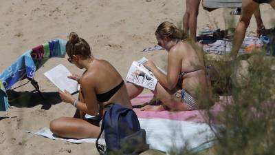 Dos jóvenes toman el sol a mediodía en la playa de Capellans en Salou. Los psicólogos defienden que cada uno tiene que aceptar el color natural de su piel sin dejarse llevar por modas. Foto: pere ferré