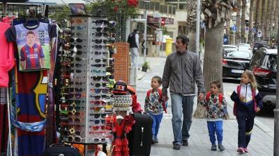 Un hombre con tres niños pasa por delante de un establecimiento multimarca, en la calle Barcelona de Salou. Foto: Pere Ferré