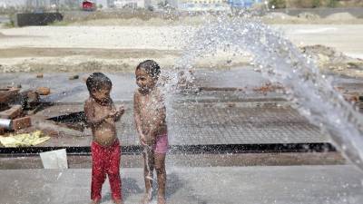 Dos niños se refrescan con una manguera durante uno de los días más calurosos en Nueva Delhi, el pasado mes de abril. Foto: EFE