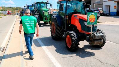 Un pagès camina al costat de la columna de tractors que ha sortit de Batea per anar a protestar a la seu de la CHE a Saragossa. Foto: EFE