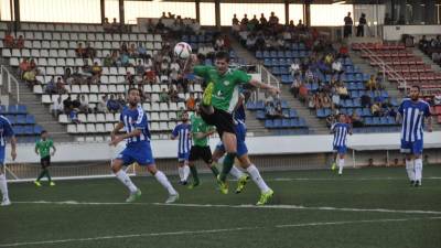 El ariete del Ascó Asier salta para controlar un balón aéreo entre futbolistas del Figueres. Foto: Iris Solà