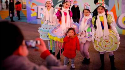 Una niña posa con artistas mientras desfilan para celebrar el día de Navidad frente a un complejo comercial en Beijing, China, el 25 de diciembre de 2020. Las tradiciones navideñas en Beijing, la capital de China, se han vuelto apreciadas no solo entre los extranjeros sino también entre los locales. EFE / EPA / WU HONG&nbsp;