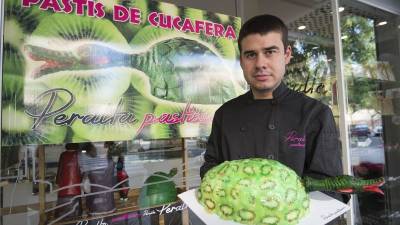 El pastisser Isidre Peralta, amb el pastís de la cucafera a les mans recobert de rodanxes de kiwi, ahir a la tarda. Foto: JOAN REVILLAS