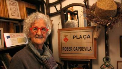 La il·lustradora, creadora de ‘Les Tres Bessones’, Roser Capdevila amb el rètol d’una plaça amb el seu nom. Foto: ACN