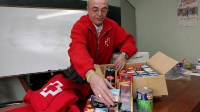 Un voluntario de Cruz Roja preparando un kit con alimentos y mantas para los usuarios de la entidad solidaria. FOTO: ALBA MARINÉ