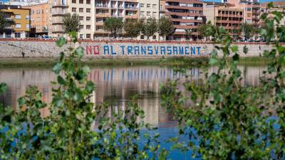 El riu Ebre al seu pas per Tortosa amb l’emblemàtica pintada contra el transvasament al mur de la seua llera. Foto: Joan Revillas