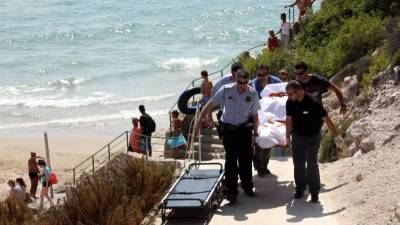 Mossos y trabajadores de una funeraria retiran, el pasado 9 de agosto de 2014, el cadáver de una mujer que se ahogó en la Platja Llarga de Salou. ACN