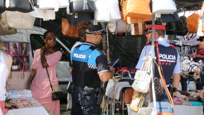 Un Polic&iacute;a Local y un Mosso d‘Esquadra comprueban que el g&eacute;nero de la parada sea legal. Foto: Alba Marin&eacute;
