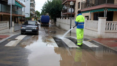 Treballadors de l'Ajuntament de Salou netejant amb aigua a pressió el fang del carrer de València del barri de la Salut. Foto: ACN