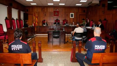 Dos mossos de espaldas, los magistrados, la fiscal, dos letrados y los cuatro acusados. Foto: ACN