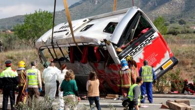 Efectius mirant com la grua està aixecant l’autobús accidentat a l’AP-7 a Freginals, el 20 de març del 2016. Foto: Jordi Marsal (ACN)