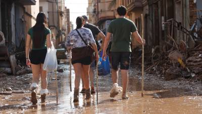 Varias personas caminan entre el lodo acumulado en las calles a causa de las intensas lluvias caídas por la fuerte dana, este jueves en Catarroja. Catarroja, una de las localidades afectadas por la dana que asoló este martes la provincia de Valencia, se afana por restablecer los suministros cortados a consecuencia del temporal y en ofrecer ayuda humanitaria a los vecinos. Foto: EFE