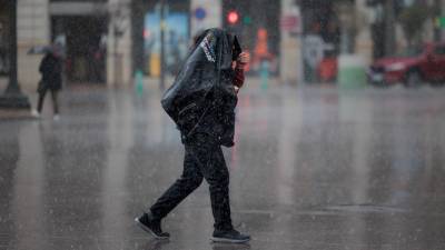 Un hombre camina bajo la lluvia en Valencia. Varias zonas de Andalucía, Aragón, Cataluña y Galicia se encuentran este sábado en alerta naranja por viento, precipitaciones, que serán en forma de nieve en cotas altas, y fenómenos costeros en el caso de Galicia, según informa la Agencia Estatal de Meteorología (AEMET). Foto: EFE