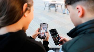 Jóvenes con un móvil consultando redes sociales como TikTok. Foto: Alba Mariné