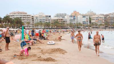 Numerosos turistas disfrutan de la playa de Llevant de Salou, con edificios de apartamentos y hoteles al fondo. Foto: Alba Mariné