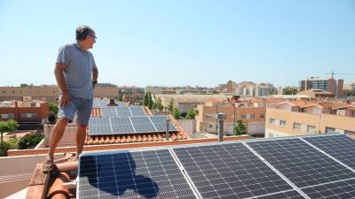 Un vecino del barrio La Mineta junto a las placas solares de su casa y otras del vecindario visibles, también. Foto: Alba Mariné