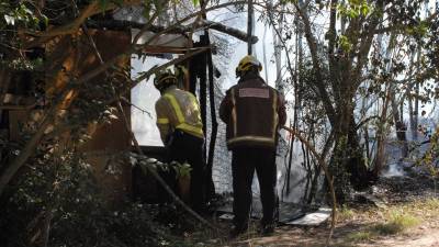 Dos bomberos accediendo a uno de los huertos afectados por el incendio. Foto: Àngel Juanpere