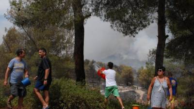 Els veïns, ahir, fent front al foc amb el què tenien a mà. Foto: Àngel Juanpere