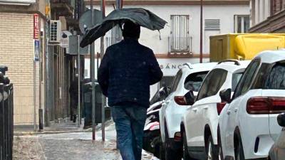 Un hombre camina con el paraguas casi destrozado por la calle. Foto: EFE
