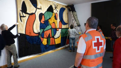 Tècnics del Museu d'Art Modern de la Diputació de Tarragona i voluntaris de la Creu Roja instal·lant el Tapís de Tarragona, de Joan Miró i Josep Royo, al seu espai de l'exposició permanent. Foto: ACN