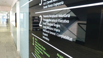 Imagen de uno de los plafones de cristal del Ayuntamiento de Salou con la información de los diferentes departamentos en catalán. FOTO: ALBA MARINÉ