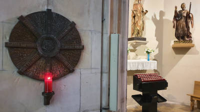 L&rsquo;espelma que crema a la Prioral de Sant Pere, sota una estela amb el nom de les parr&ograve;quies de Reus, al costat de la capella de Santa Ll&uacute;cia.