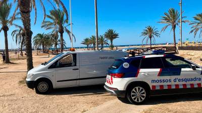 Una patrulla de los Mossos d’Esquadra y un vehículo de la funeraria, esta mañana en la playa de Coma-ruga.