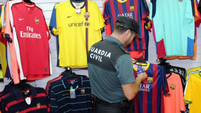 Un Guàrdia Civil observant l'etiqueta d'una de les samarretes intervingudes a Salou. FOTO: ACN.