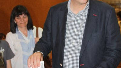 El candidat de CiU i alcalde de Tortosa, Ferran Bel, votant al centre multiús de Remolins, amb la seva dona al darrere. Foto: ACN