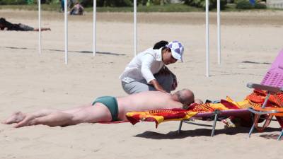 Una mujer ofrece un masaje en la arena a un turista. Foto: Alba Mariné/DT
