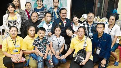 El primer ministro tailandés, Prayut Chan-o-cha (c), posa junto a familiares de los niños atrapados. FOTO: EFE