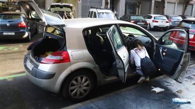 Una mujer limpia el interior de su coche afectado por el aguacero de las últimas horas. FOTO: ACN