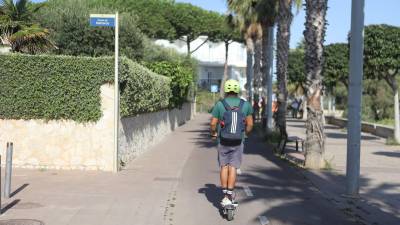 Un joven en patinete, pasando por la zona donde se accidentó la joven, en la calle Menorca junto al Passeig Marítim. Foto: Alba Mariné
