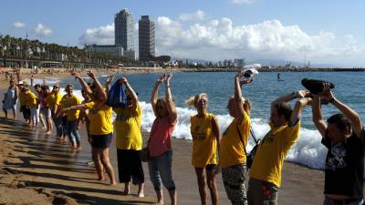 Vecinos de la Barceloneta haciendo la ola en la playa en la concentración en defensa del barrio y en contra de los efectos de la masificación del turismo. Foto: EFE