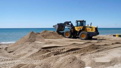 Una excavadora extiende la arena.