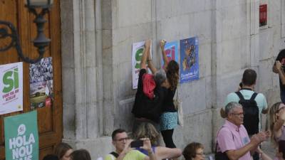 Los ediles de la CUP en Tarragona, Jordi Martí y Laia Estrada, pegando carteles en la fachada del consistorio. Foto: lluís milian