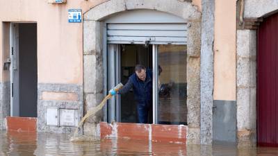 Un hombre achica agua de su vivienda tras el desbordamiento del río Ter ayer por la tarde en el barrio de Pont Major de la ciudad de Girona. FOTO: EFE