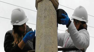 Les restauradores Olga Schmid i Marina Ramisa instal·lant la creu a Ulldecona. FOTO: JORDI MONFORTE